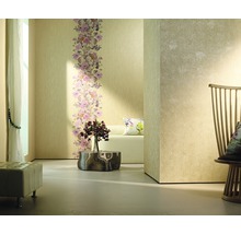 Pièce lumineuse avec bordure florale sur un papier peint, complétée par des fauteuils et des décorations.