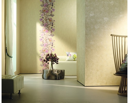 Pièce lumineuse avec bordure florale sur un papier peint, complétée par des fauteuils et des décorations.