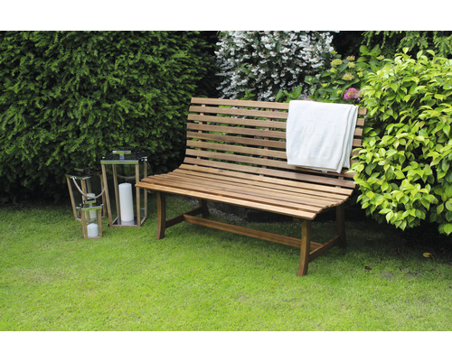 Gartenszene mit einer Holzbank, Windlichtern und einem Tuch auf einer Rasenfläche