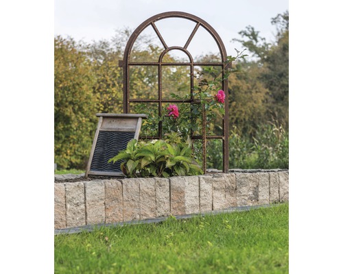 Jardin décoratif avec cadre de fenêtre en métal, planche à laver et mur en pierre.