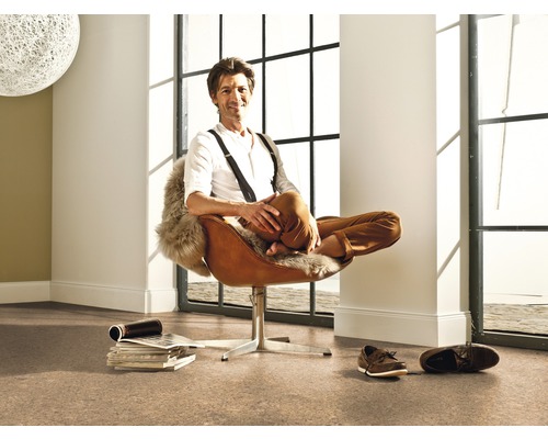 Pièce lumineuse avec sol en liège et homme assis dans un fauteuil marron