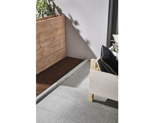 Scène avec jardinière en bois, siège et dalles de terrasse grises.