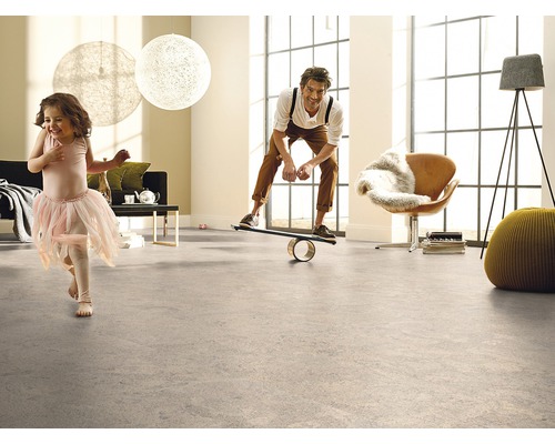 Salon lumineux avec revêtement de sol, dans lequel un homme se tient sur une planche d''équilibre et un enfant se promène