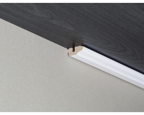 Sockelleiste aus Holz, angebracht an einer Wand und einem dunklen Holzboden