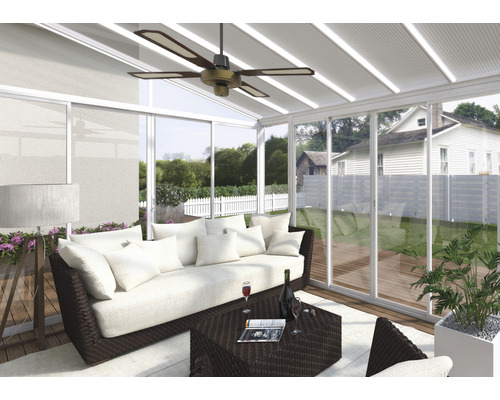 Salon dans une véranda avec canapé, table et ventilateur de plafond