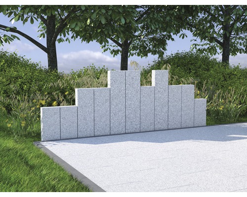 Mur de jardin décoratif en granit devant des buissons et des arbres