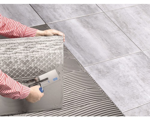 Carreleur posant des carreaux avec une truelle sur une surface
