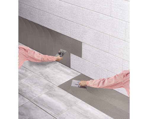 Carreleur appliquant de la colle à carrelage sur des carreaux muraux et de sol