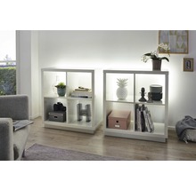 Zwei weisse Regale mit Fächern und Dekorationsartikeln in einem Wohnzimmer.