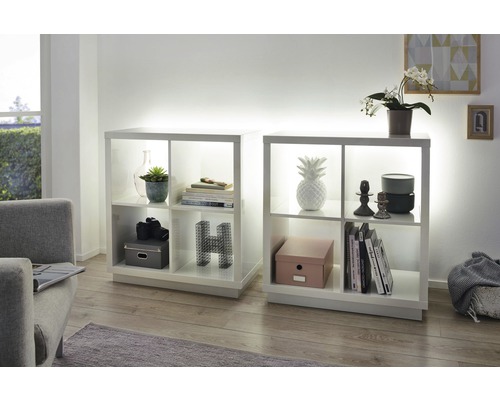 Zwei weisse Regale mit Fächern und Dekorationsartikeln in einem Wohnzimmer.