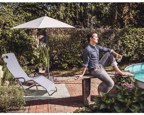 Szene im Garten mit Liegestuhl, Sonnenschirm und entspanntem Mann
