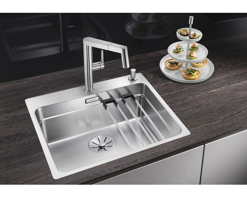 Évier en acier inoxydable avec égouttoir et robinet sur un plan de cuisine.
