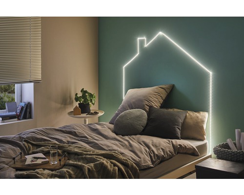 Schlafzimmer mit Bett, Nachttisch und LED-Lichtern in Hausform an der Wand