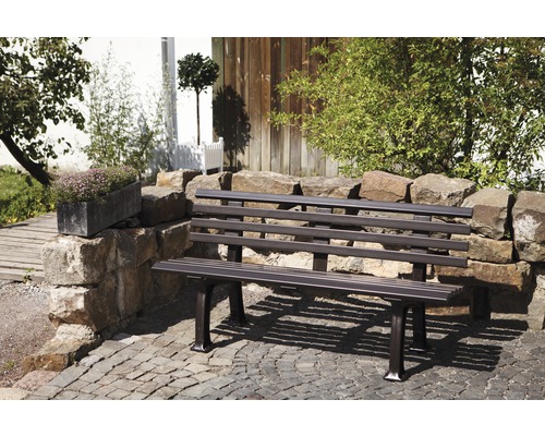 Banc de jardin en métal devant un mur de pierre