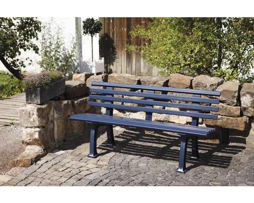 Un banc de jardin en métal se trouve sur une place pavée dans un jardin.