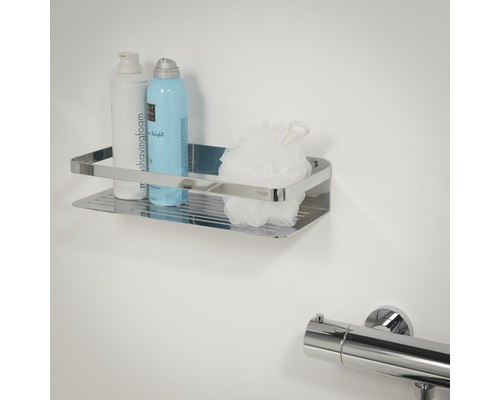 Étagère de douche chromée avec produits de soin et éponge de bain fixée au mur.