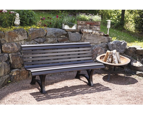 Banc de jardin en bois et métal devant un mur de pierre avec décoration