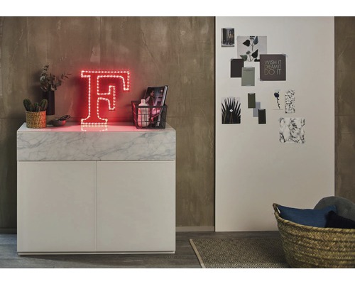 Szene mit beleuchtetem Buchstaben F auf einem Sideboard mit Dekorationsgegenständen.