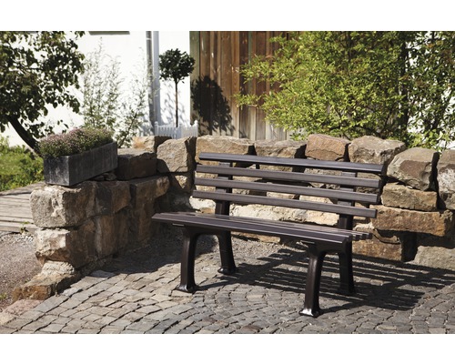 Banc de jardin en métal devant un mur de pierre