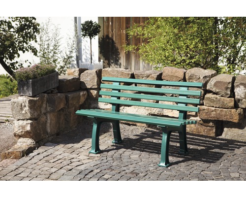 Grüne Gartenbank aus Holz und Steinmauer im Aussenbereich