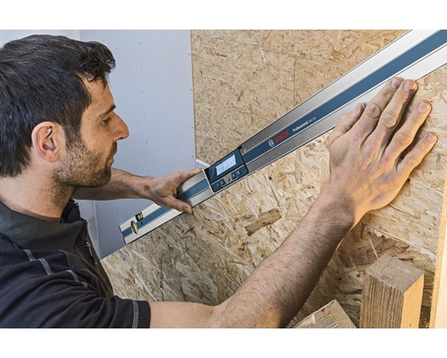 Artisan mesurant un angle avec un rapporteur d'angle numérique Bosch sur une plaque de bois