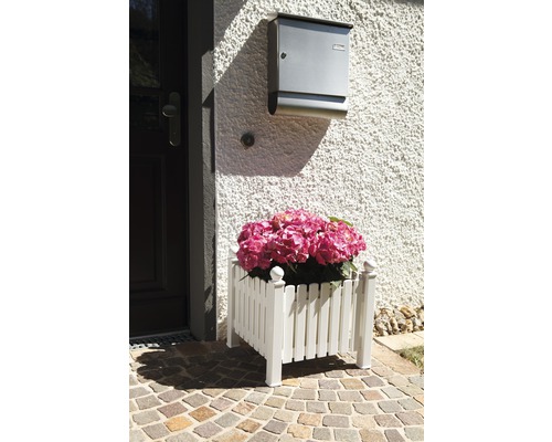 Jardinière décorative en bois avec des hortensias roses devant une porte d''entrée.