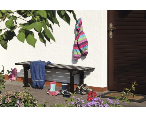 Szene mit Bank, Kinderkleidung und Schuhen vor einem Haus