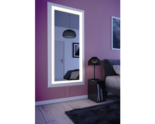 Beleuchteter Spiegel im Schlafzimmer mit Nachttisch und Bett