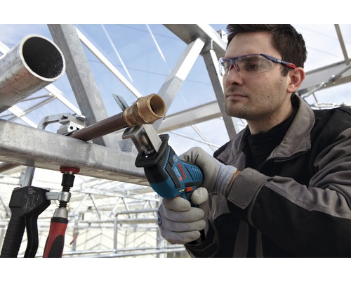 Un homme scie un tuyau avec une scie sabre Bosch