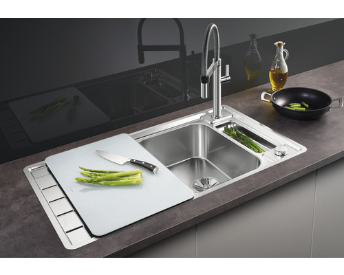Évier en acier inoxydable avec planche à découper et robinet sur un plan de travail