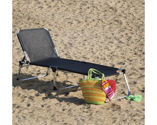 Strandliege mit Strandtasche und Accessoires im Sand