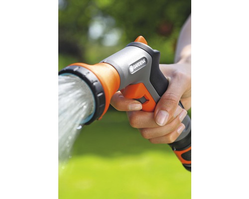 Une main tient une douche de jardin Gardena d''où s''écoule de l''eau.
