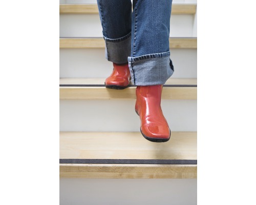 Personne en bottes descendant un escalier avec des bandes antidérapantes