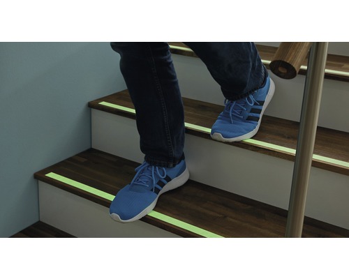 Person steigt Treppe mit Antirutschstreifen hinauf.