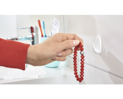 Person hängt Armband an einem Wandhaken im Badezimmer auf