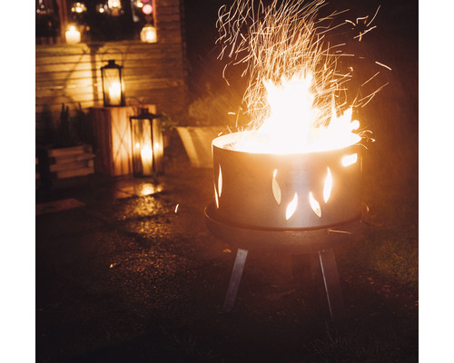 Brennendes Feuer in einer Feuerstelle mit Ausschnitten im Garten