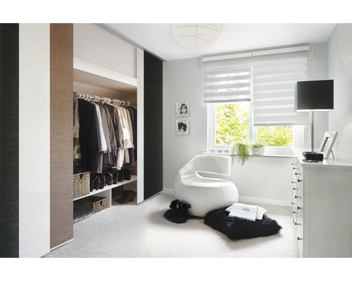 Chambre à coucher lumineuse avec armoire à portes coulissantes, store enrouleur et fauteuil moderne