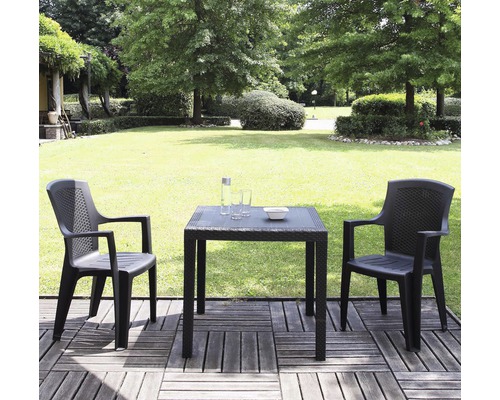 Gartenszene mit Tisch, zwei Stühlen, Trinkflasche, Gläsern und Schale auf einer Terrasse