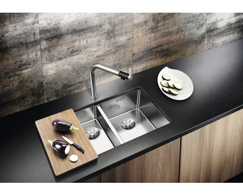 Évier en acier inoxydable avec robinetterie et planche à découper sur un plan de travail de cuisine