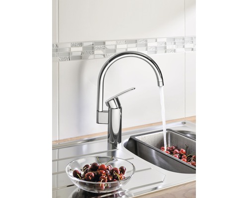 Robinet de cuisine avec de l''eau coulant dans un évier à côté d''un bol de cerises