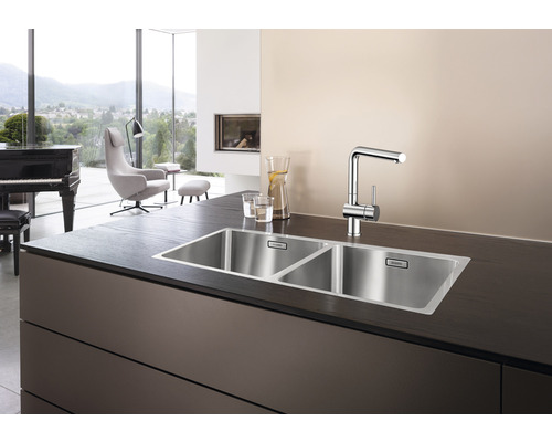 Évier en acier inoxydable à deux bacs avec robinet sur un plan de travail.