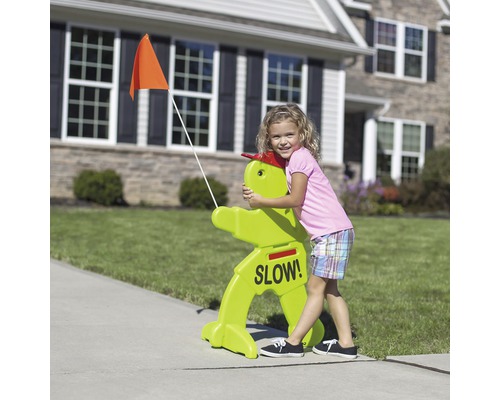 Enfant étreignant un panneau de signalisation vert avec l''inscription « Lentement ! » et un drapeau orange
