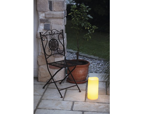 Scène de jardin décorative avec une chaise pliante en métal, une plante en pot et une lanterne