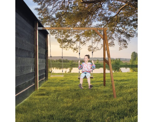 Mädchen schaukelt auf einer Holzschaukel im Garten