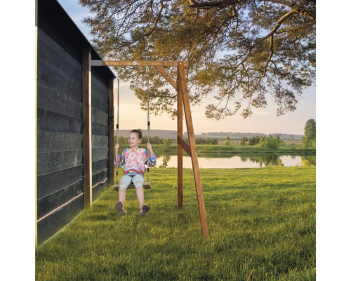 Fille se balançant sur une balançoire en bois dans le jardin devant un lac.