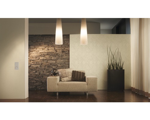 Wohnzimmer mit Sessel, Stehlampe, Zimmerpflanze und Steinwand