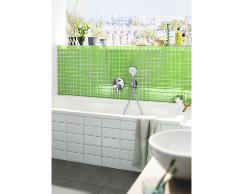 Salle de bains moderne avec baignoire, carreaux de mosaïque verts et fenêtre avec vue sur la ville