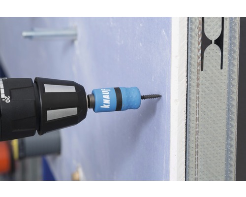 Un tournevis visse une vis dans une plaque de plâtre.