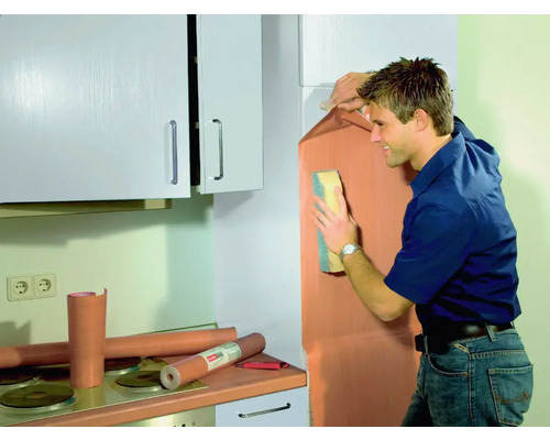 Mann bringt Möbelfolie in einer Küche an