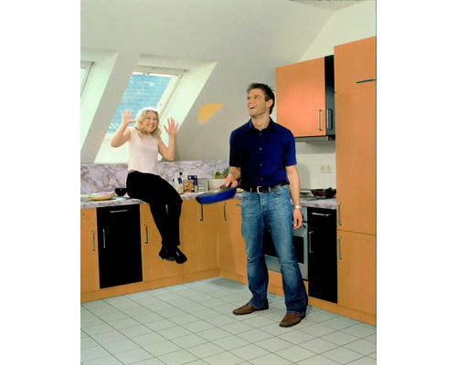 Heller Raum mit Paar, Mann mit Pfanne, Frau sitzt auf Küchentheke.